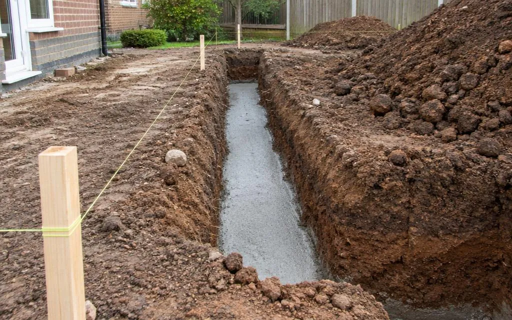 Excavated foundation trench with poured concrete and setting-out string lines